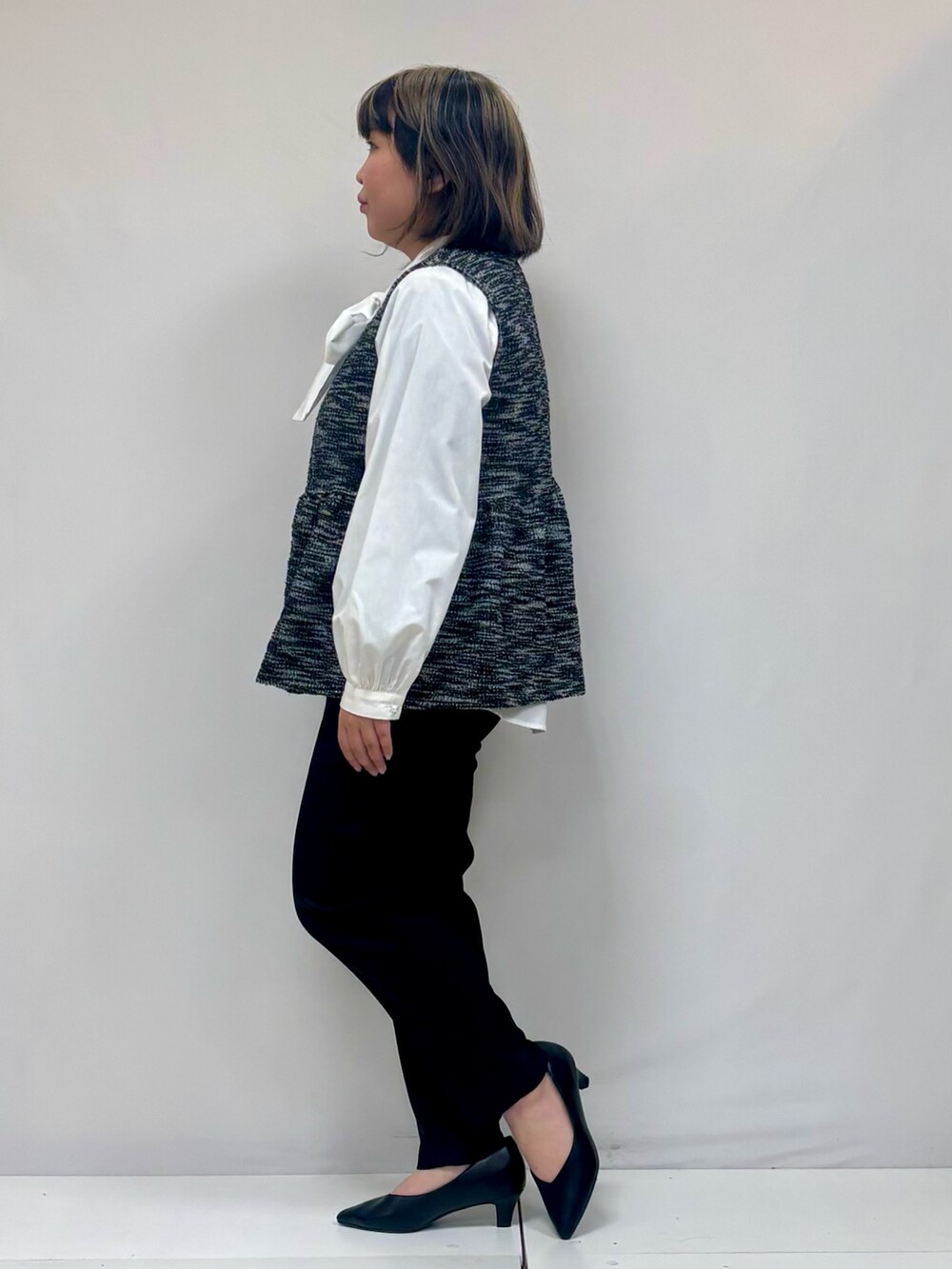 ホワイト系のシャツ/ブラウス、ブラック系のベスト、ブラック系のその他パンツを着用したレディースの春コーディネートの2枚目の写真