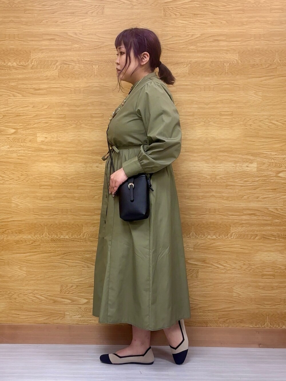 グリーン系のワンピース、ブラック系のパンプス、ブラック系のショルダーバッグを着用したレディースの春コーディネートの2枚目の写真