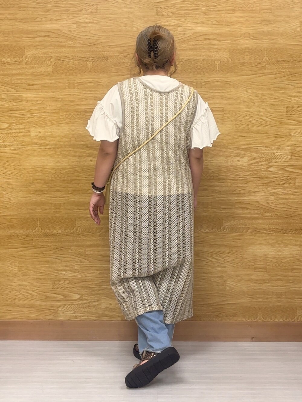 ホワイト系のTシャツ/カットソー、ベージュ系のベスト、ブラック系のショルダーバッグを着用したレディースの春コーディネートの2枚目の写真