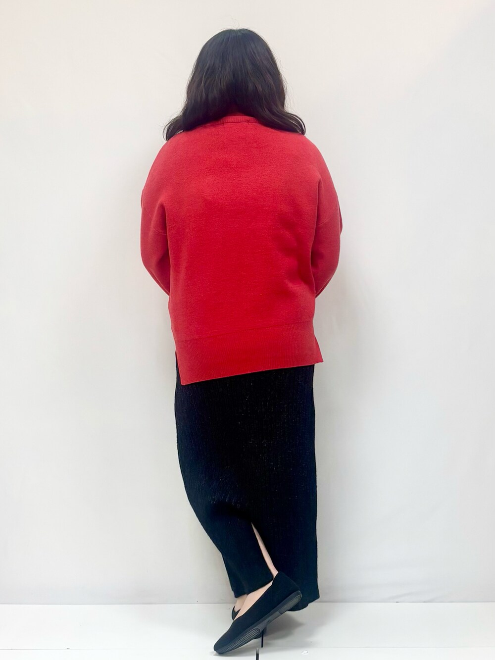 オレンジ系のニット/セーター、ブラック系のスカート、ブラック系のパンプスを着用したレディースの冬コーディネートの3枚目の写真