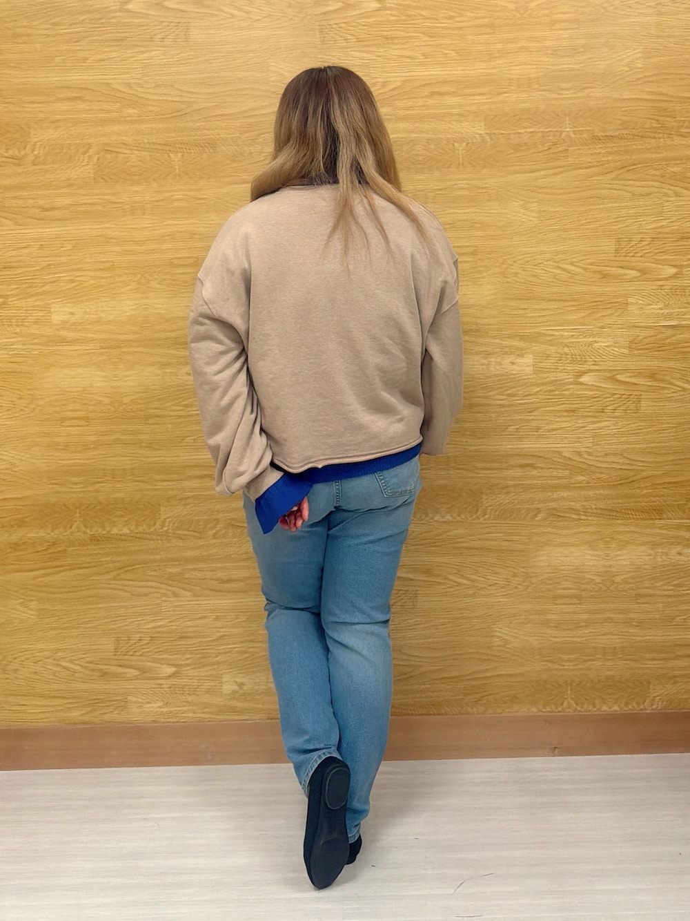 ブラウン系のスウェット、ブルー系のニット/セーター、ブルー系のデニムパンツを着用したレディースの春コーディネートの2枚目の写真