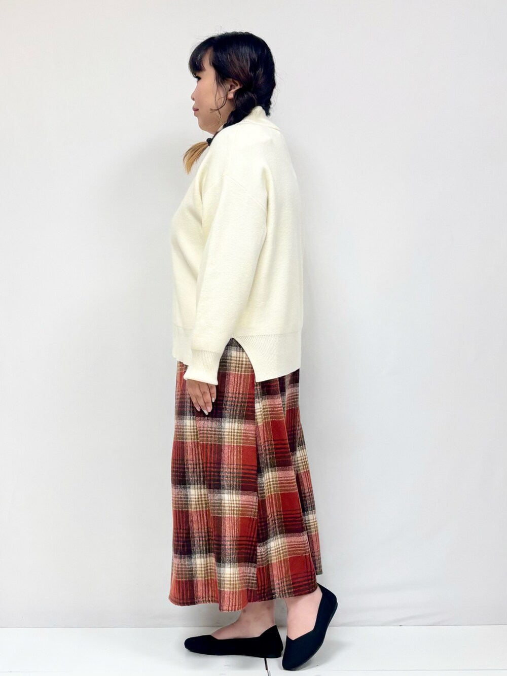 ベージュ系のスカート、ブラック系のパンプス、オレンジ系のニット/セーターを着用したレディースの冬コーディネートの2枚目の写真