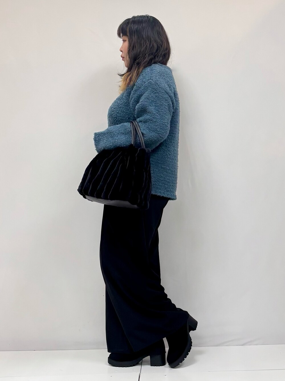 ブラック系のその他パンツ、ブルー系のニット/セーター、ブラック系のブーツを着用したレディースの冬コーディネートの2枚目の写真