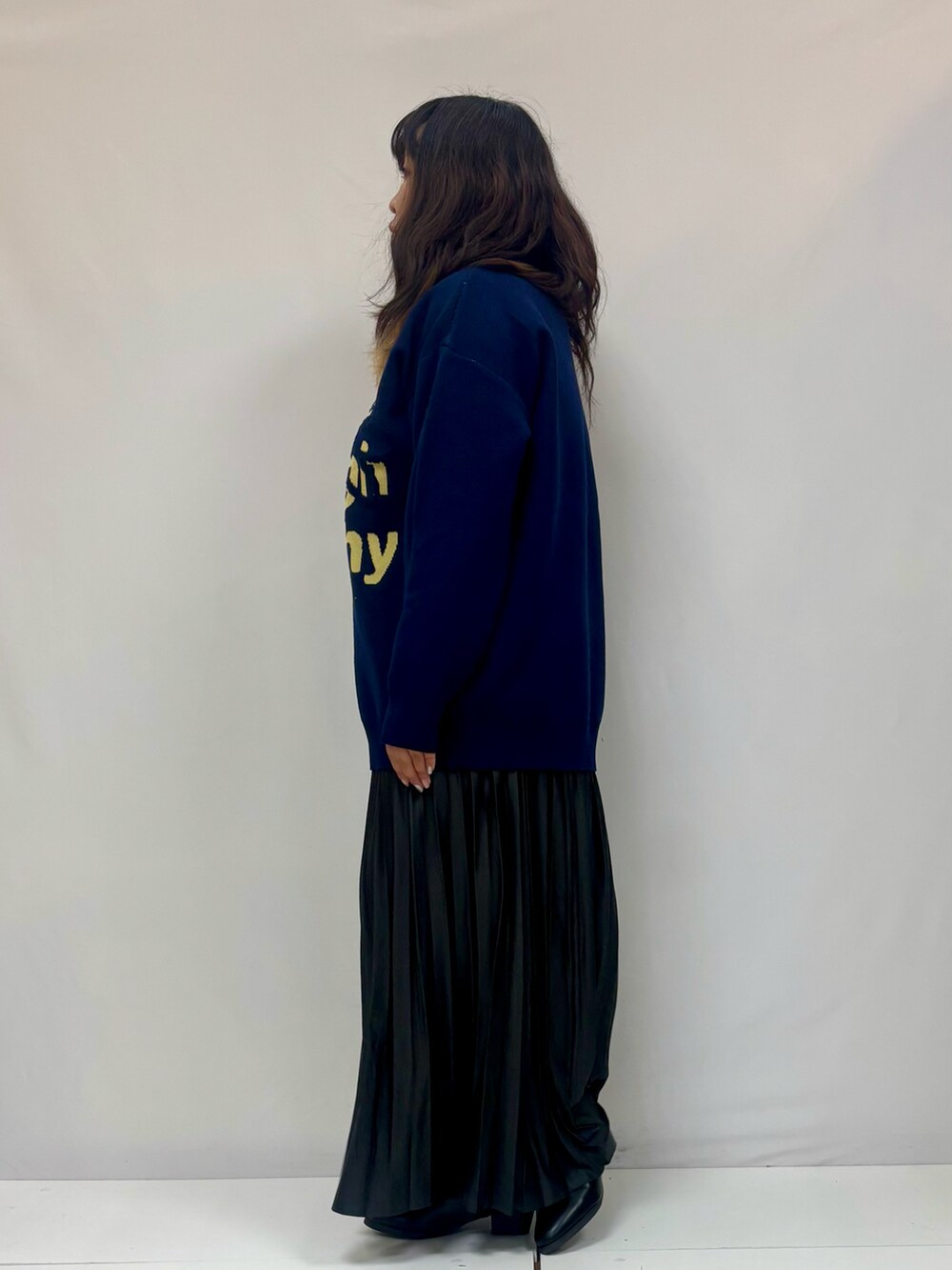 ブルー系のニット/セーター、ブラック系のスカート、ブラック系のブーツを着用したレディースの冬コーディネートの2枚目の写真