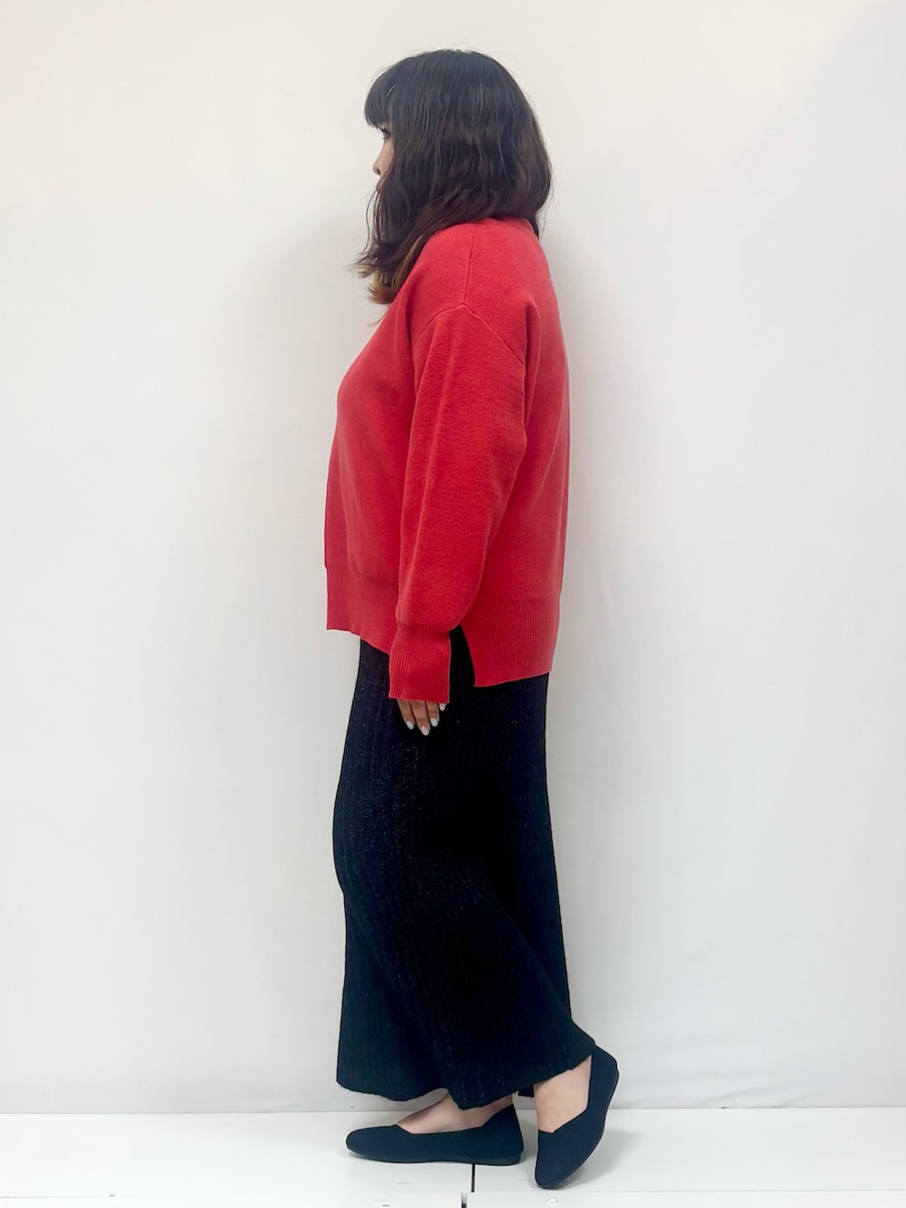 オレンジ系のニット/セーター、ブラック系のスカート、ブラック系のパンプスを着用したレディースの冬コーディネートの2枚目の写真