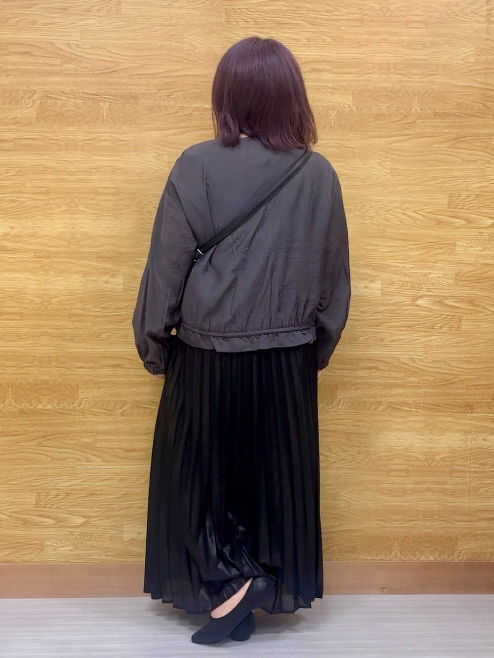 ブラック系のスカート、グレー系のブルゾン、ブラック系のショルダーバッグを着用したレディースの春コーディネートの2枚目の写真