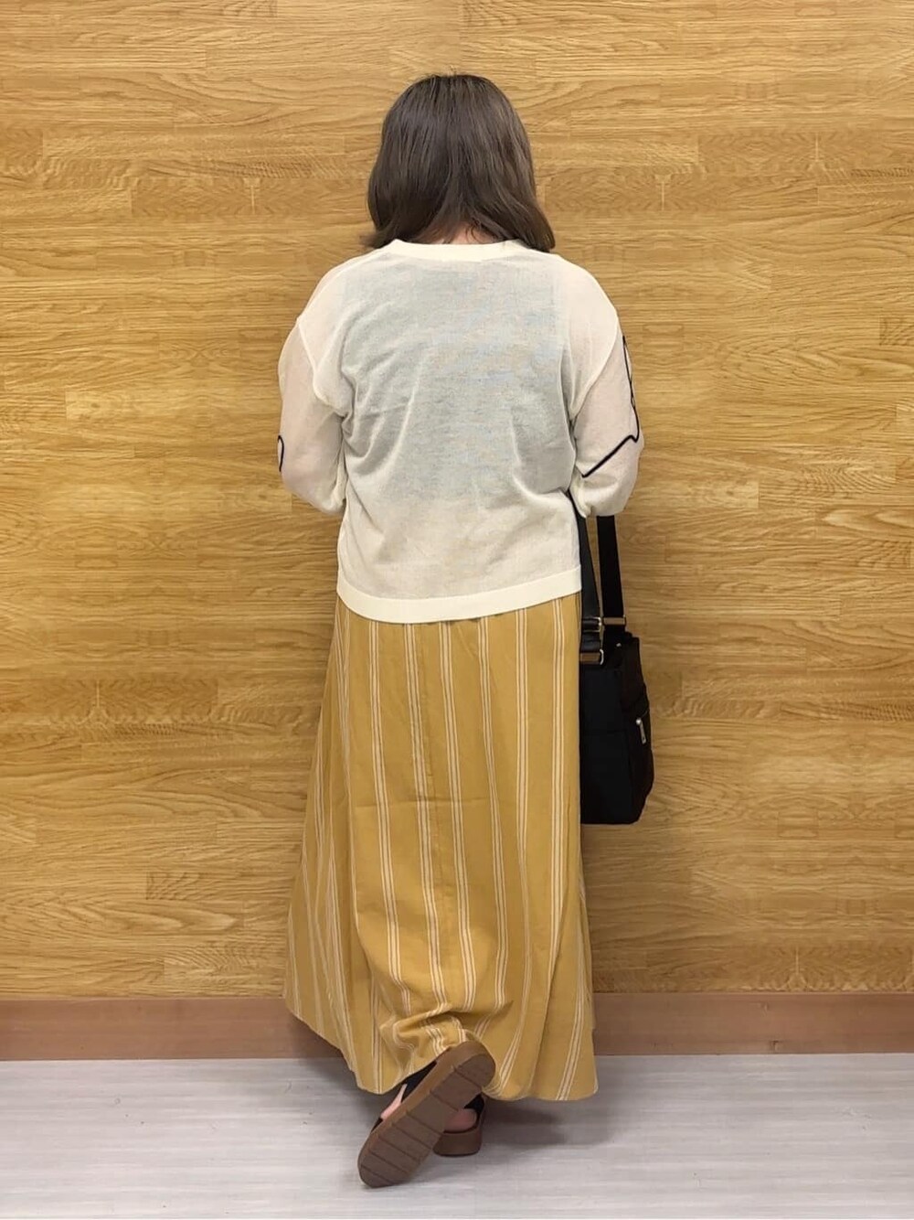ホワイト系のカーディガン/ボレロ、イエロー系のスカート、ブラック系のサンダルを着用したレディースの夏コーディネートの3枚目の写真