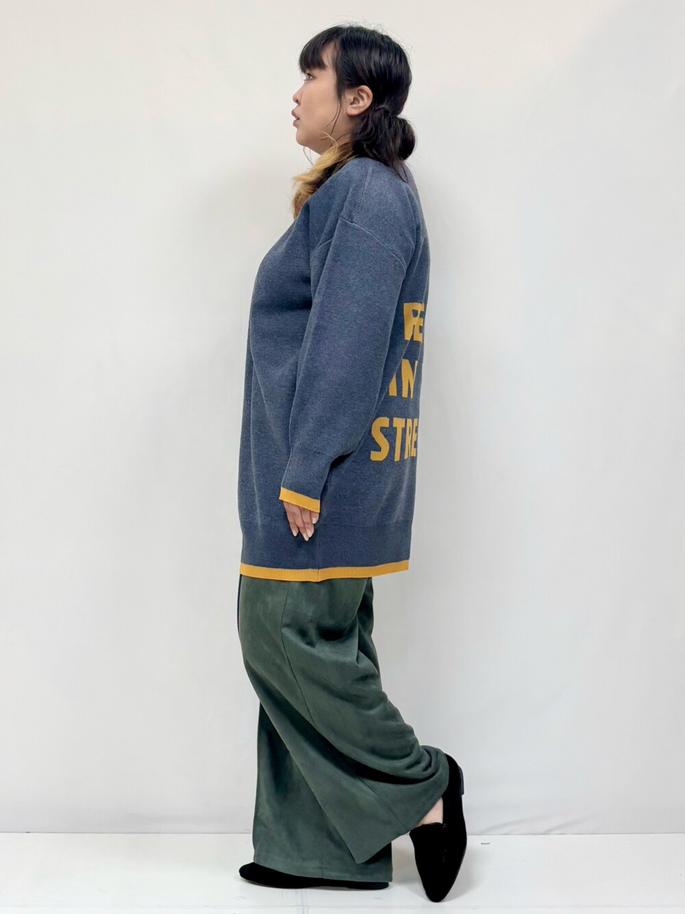 ブルー系のチュニック、グリーン系のその他パンツ、ブラック系のパンプスを着用したレディースの冬コーディネートの2枚目の写真