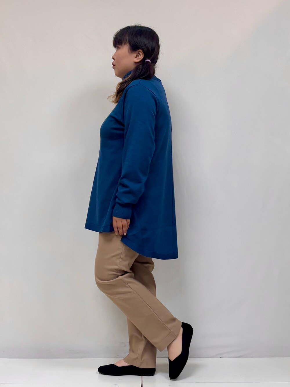 ブルー系のチュニック、ブラック系のパンプス、ブラウン系のその他パンツを着用したレディースの冬コーディネートの2枚目の写真