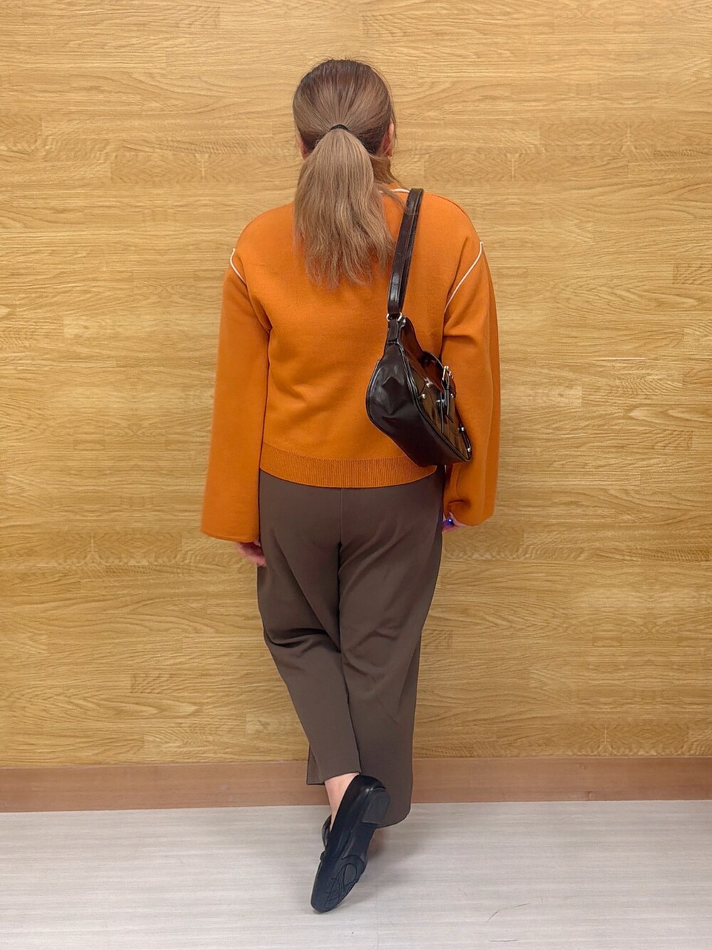 オレンジ系のニット/セーター、ブラウン系のその他パンツを着用したレディースの春コーディネートの2枚目の写真
