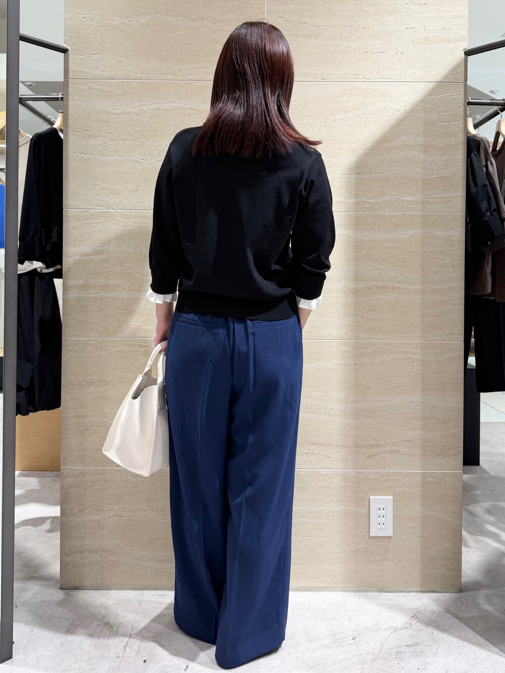 ブラック系のニット/セーター、ブルー系のその他パンツ、ホワイト系のショルダーバッグを着用したレディースの春コーディネートの2枚目の写真