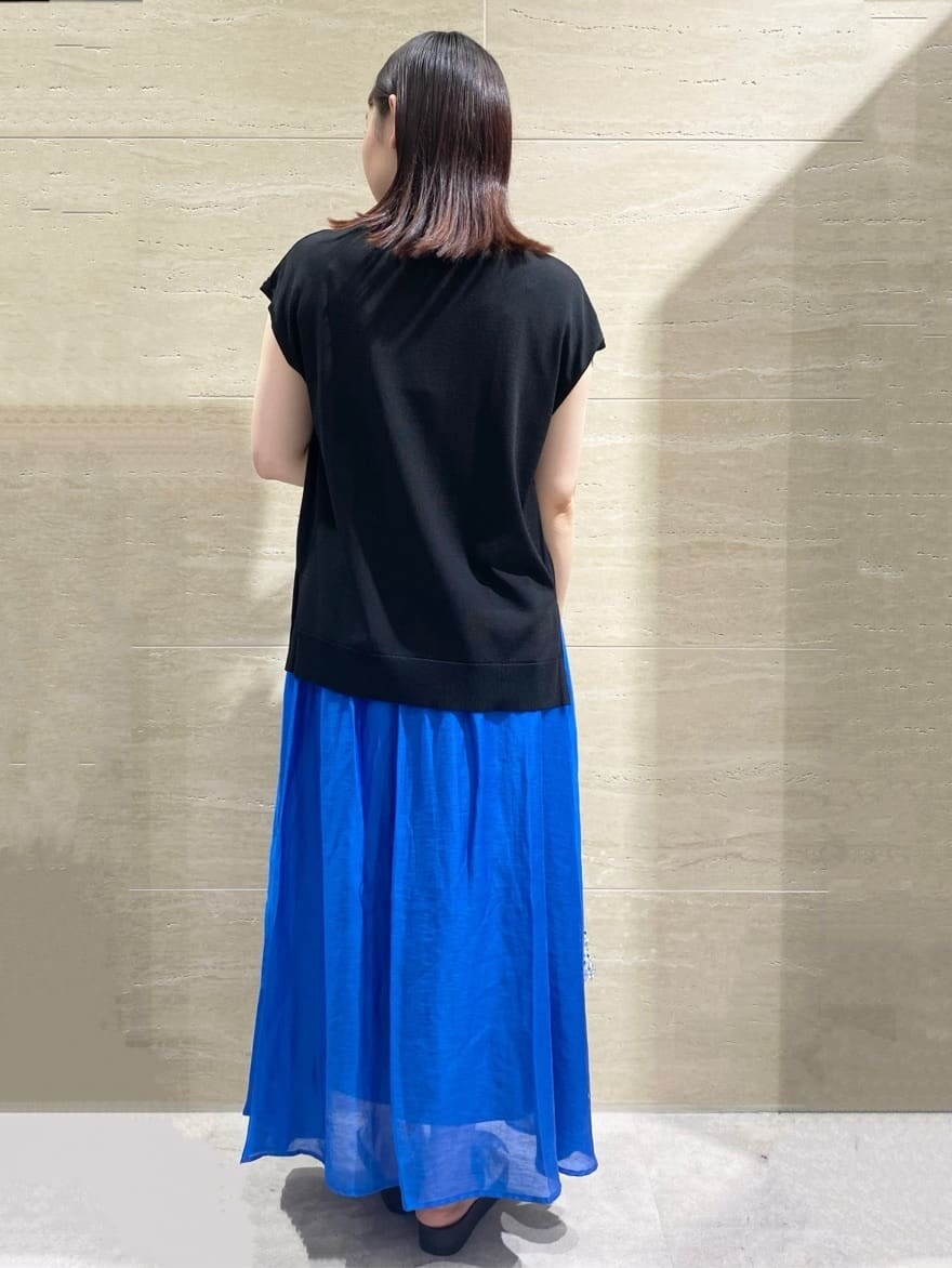 ブラック系のニット/セーター、ブルー系のスカート、シルバー系のショルダーバッグを着用したレディースの夏コーディネートの2枚目の写真