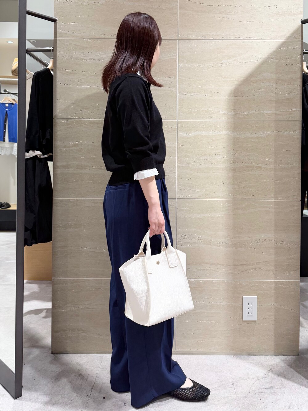 ブラック系のニット/セーター、ブルー系のその他パンツ、ホワイト系のショルダーバッグを着用したレディースの春コーディネートの3枚目の写真