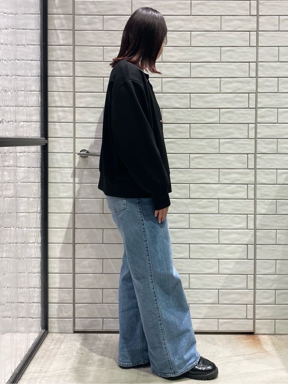 ブラック系のカーディガン/ボレロ、ホワイト系のTシャツ/カットソー、ブルー系のデニムパンツを着用したレディースの冬コーディネートの3枚目の写真