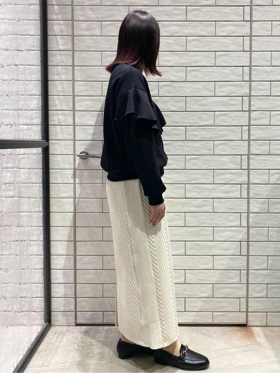 ブラック系のTシャツ/カットソー、ホワイト系のスカート、ブラック系のパンプスを着用したレディースの冬コーディネートの3枚目の写真