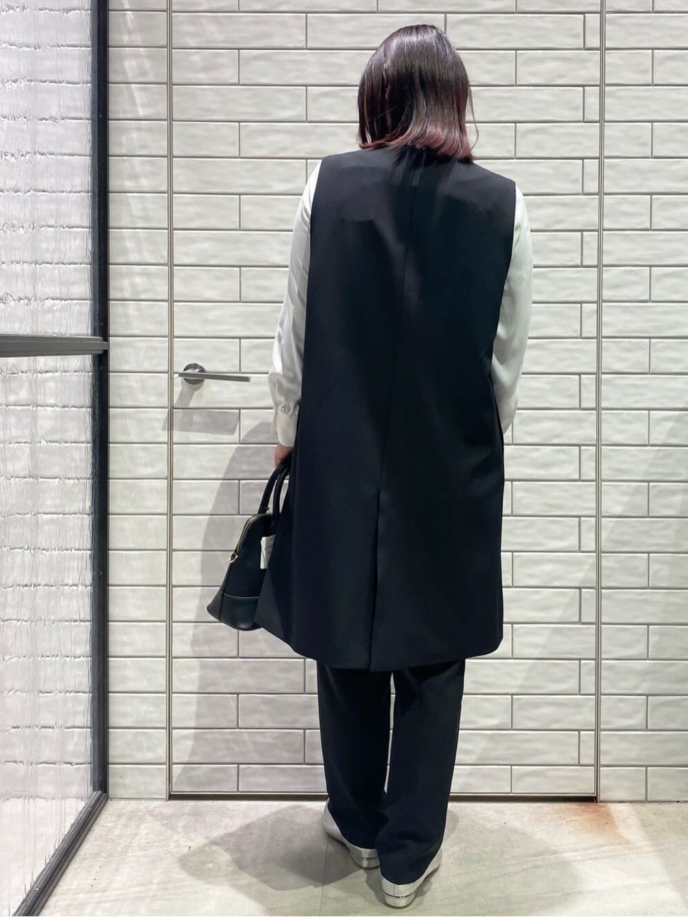 ブラック系のベスト、ホワイト系のシャツ/ブラウス、ブラック系のその他パンツを着用したレディースの冬コーディネートの2枚目の写真