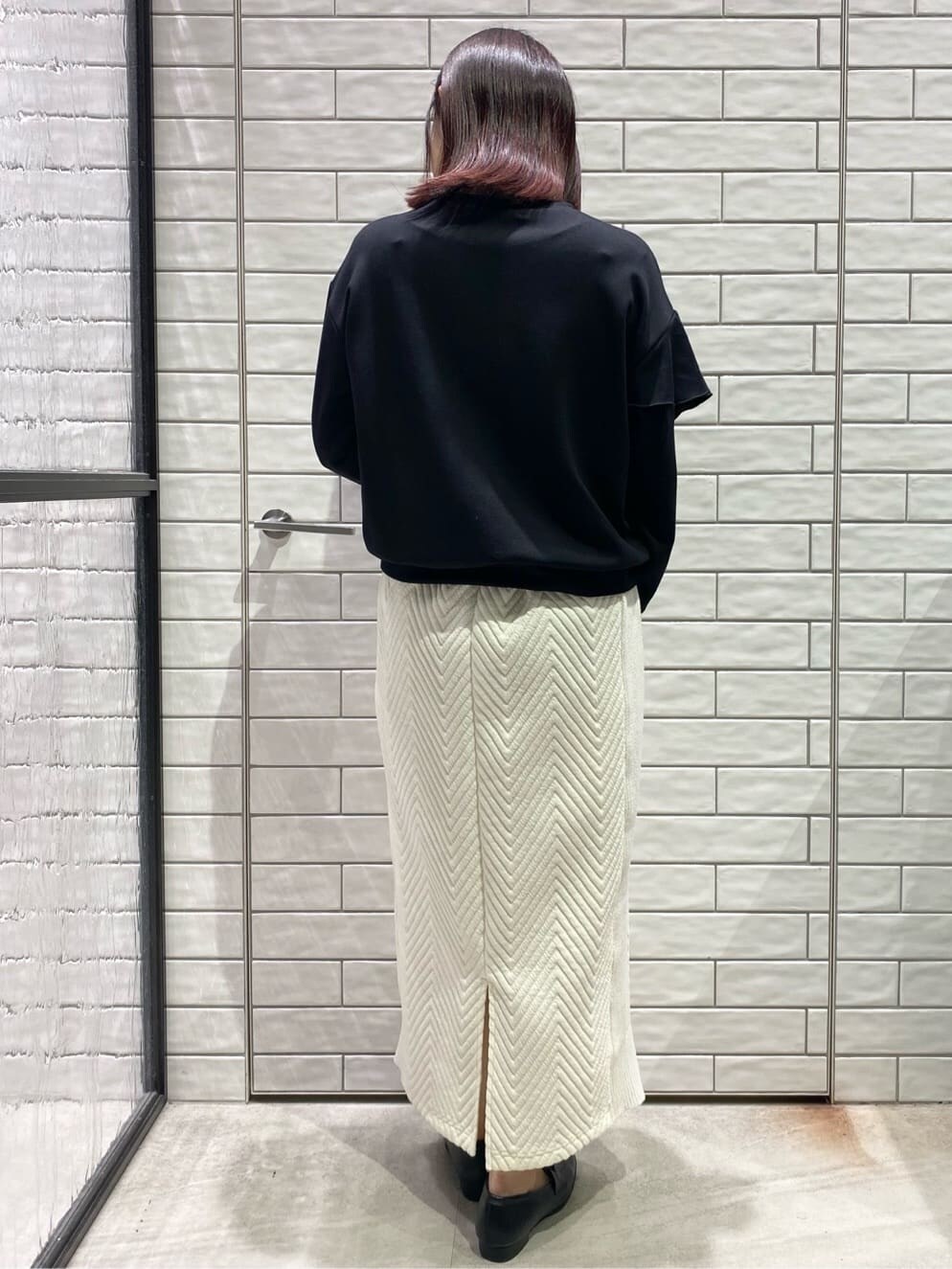ブラック系のTシャツ/カットソー、ホワイト系のスカート、ブラック系のパンプスを着用したレディースの冬コーディネートの2枚目の写真