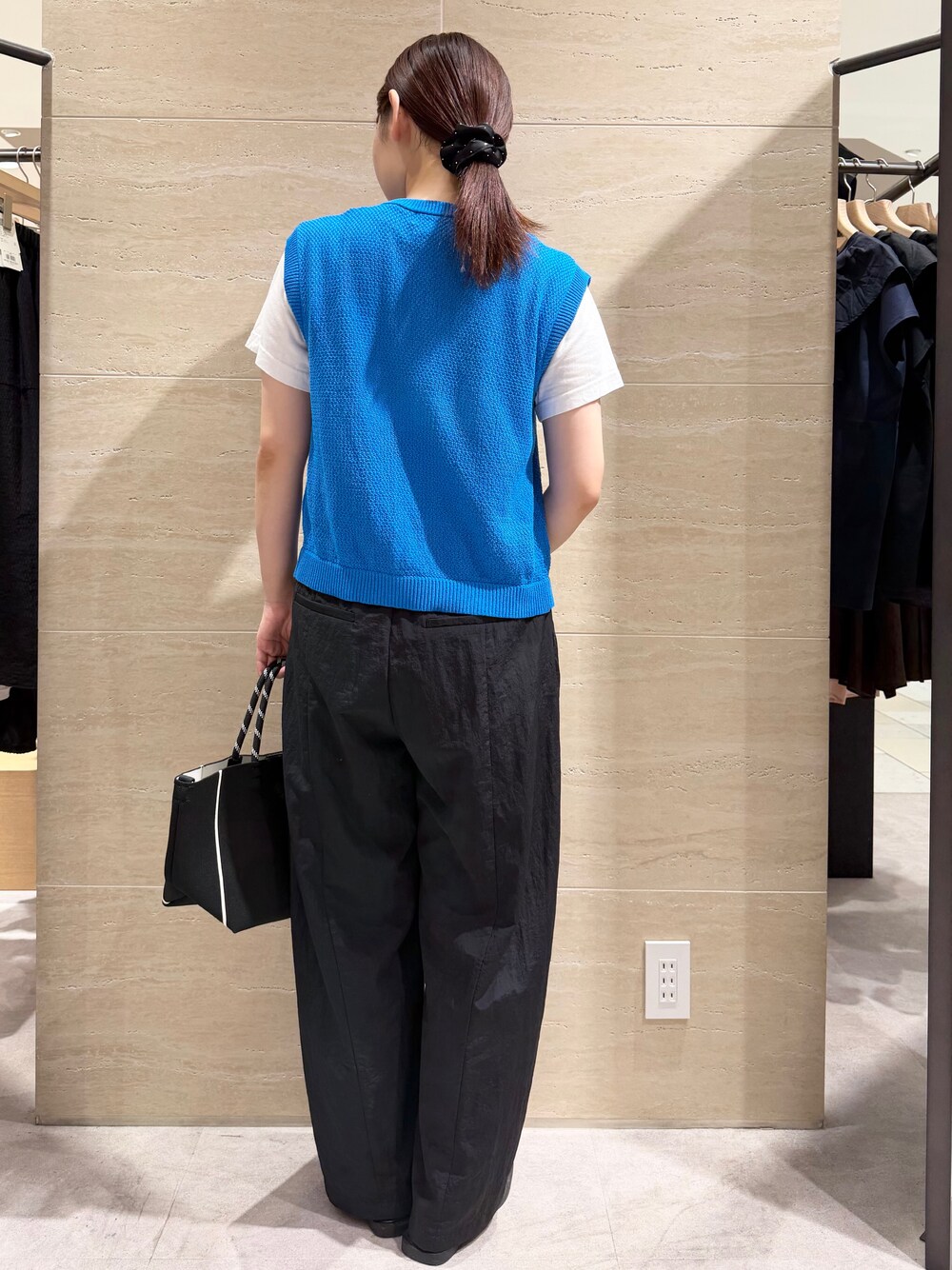 ブルー系のニット/セーター、ブラック系のその他パンツ、ブラック系のトートバッグを着用したレディースの夏コーディネートの2枚目の写真