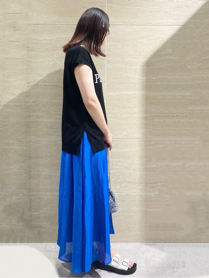 ブラック系のニット/セーター、ブルー系のスカート、シルバー系のショルダーバッグを着用したレディースの夏コーディネートの3枚目の写真