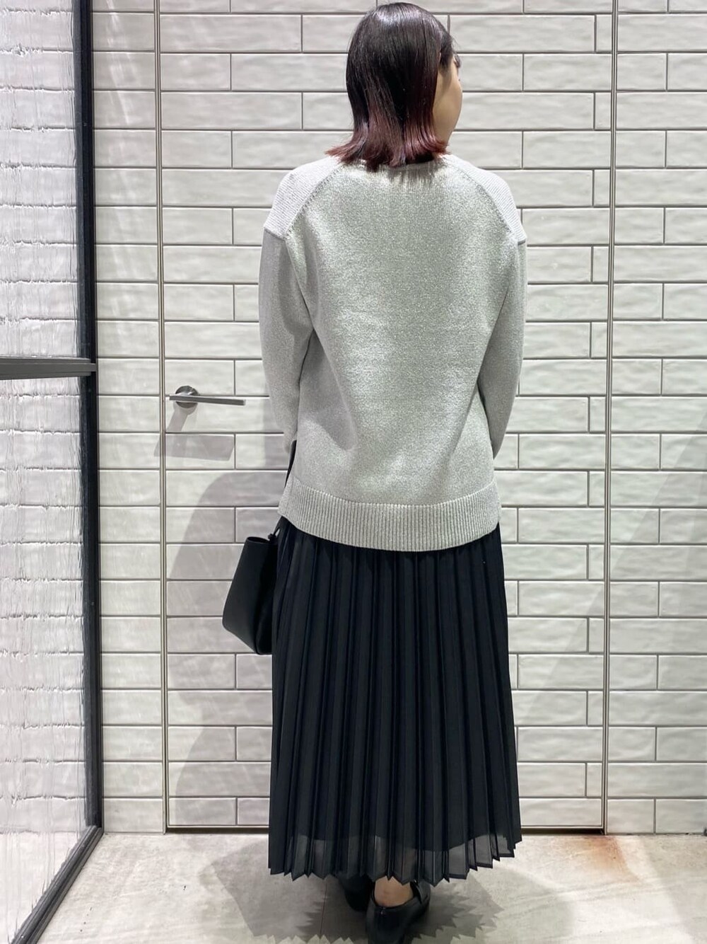 シルバー系のニット/セーター、グレー系のスカート、ブラック系のトートバッグを着用したレディースの冬コーディネートの2枚目の写真