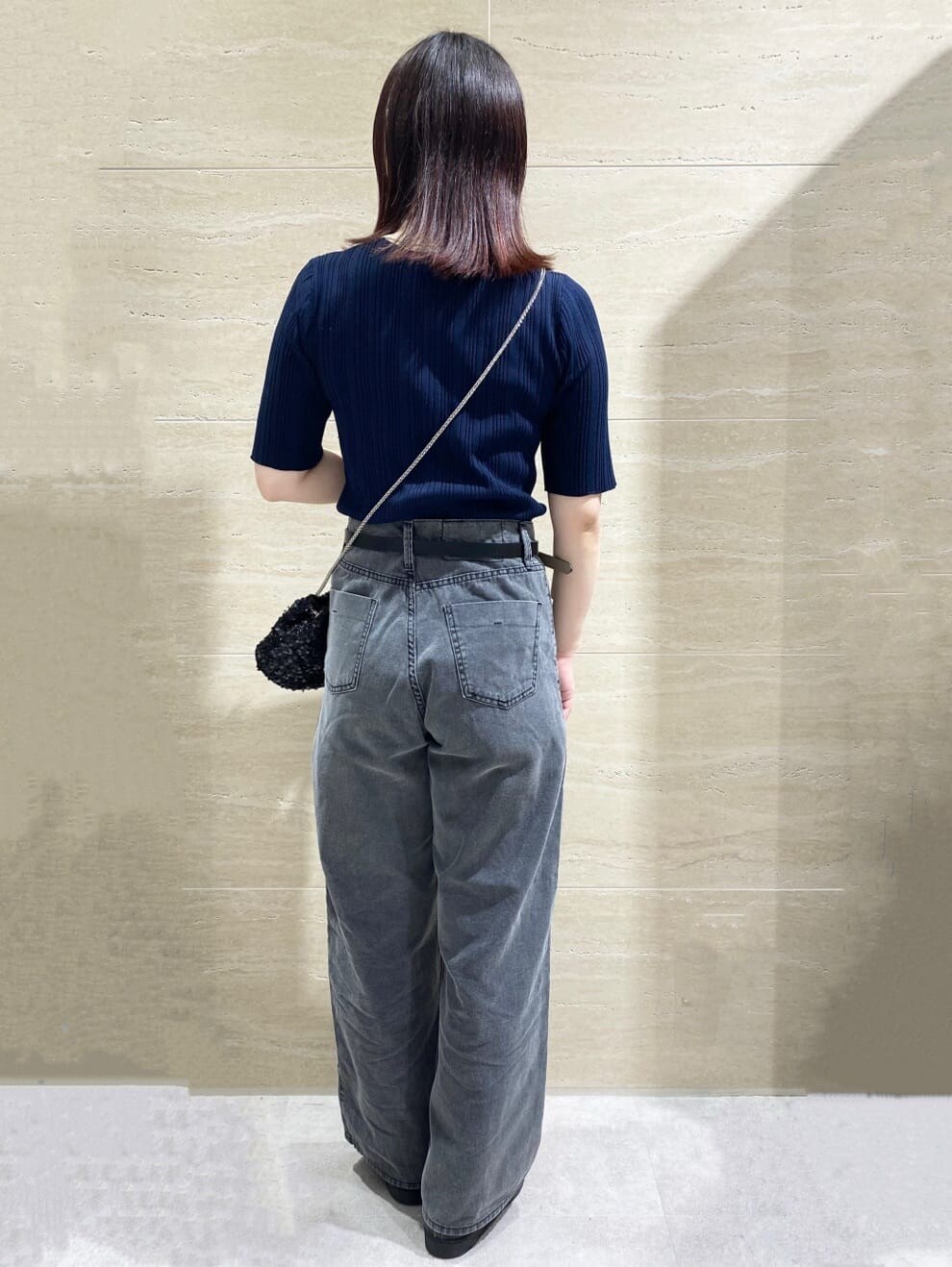 ブルー系のニット/セーター、グレー系のデニムパンツ、ブラック系のショルダーバッグを着用したレディースの春コーディネートの2枚目の写真
