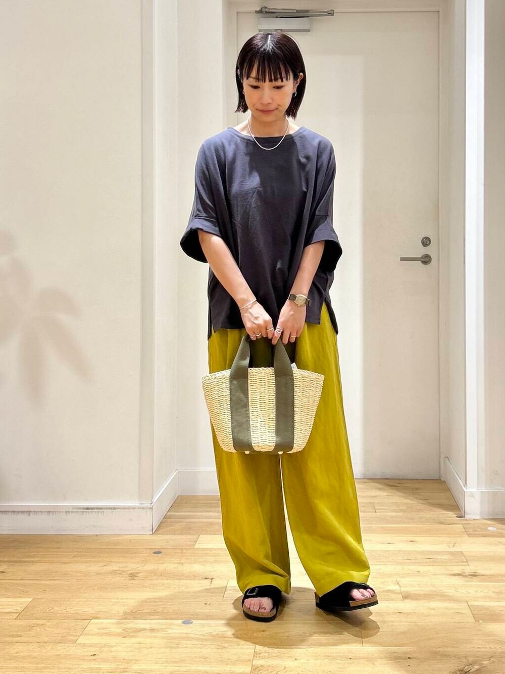 ベージュ系のかごバッグ、イエロー系のその他パンツ、ブラック系のサンダルを着用したレディースの夏コーディネートの2枚目の写真