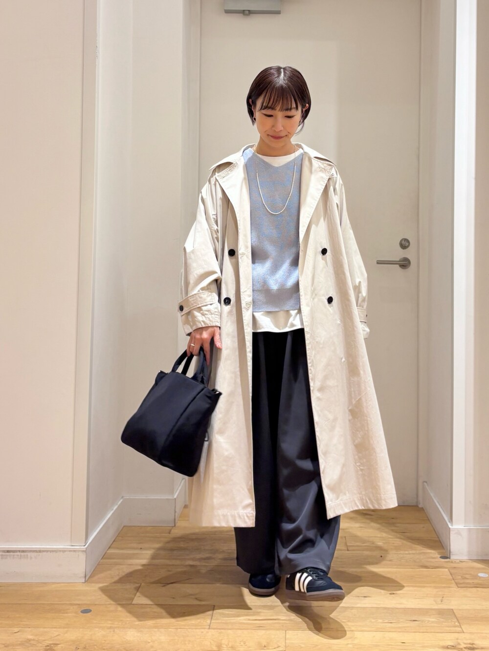 ブルー系のニット/セーター、ホワイト系のTシャツ/カットソー、ベージュ系のトレンチコートを着用したレディースの春コーディネートの4枚目の写真