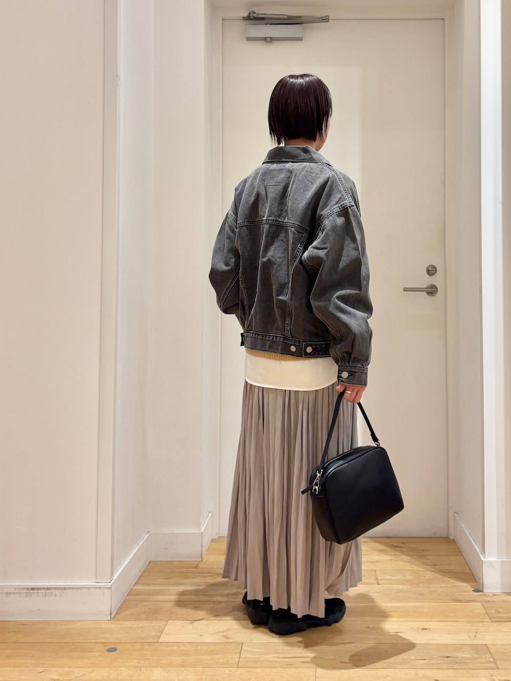 ブラック系のデニムジャケット、ベージュ系のニット/セーター、ホワイト系のTシャツ/カットソーを着用したレディースの春コーディネートの5枚目の写真