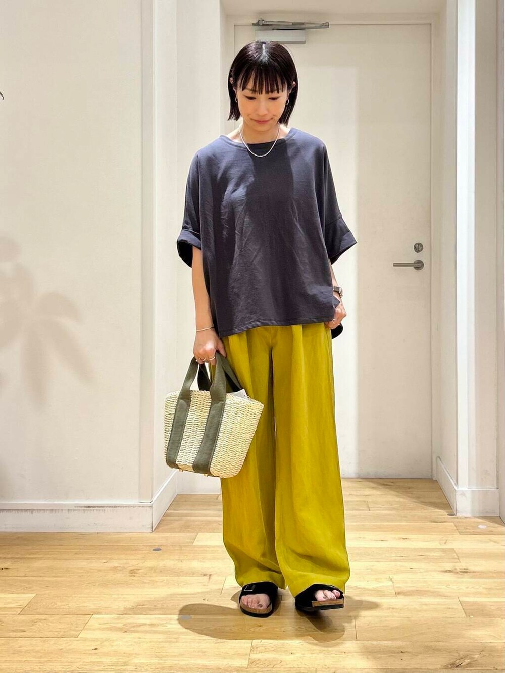 ベージュ系のかごバッグ、イエロー系のその他パンツ、ブラック系のサンダルを着用したレディースの夏コーディネートの3枚目の写真
