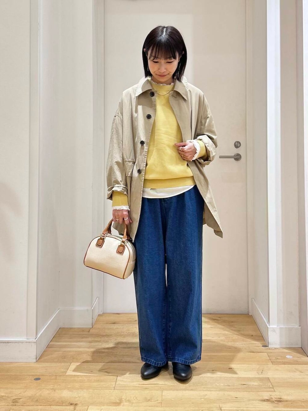 ホワイト系のシャツ/ブラウス、イエロー系のニット/セーター、ブルー系のデニムパンツを着用したレディースの冬コーディネートの2枚目の写真