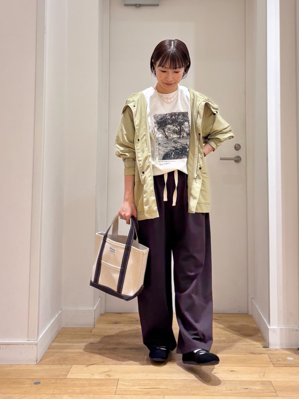 グリーン系のマウンテンパーカー、ホワイト系のTシャツ/カットソー、ブラック系のスニーカーを着用したレディースの春コーディネートの2枚目の写真