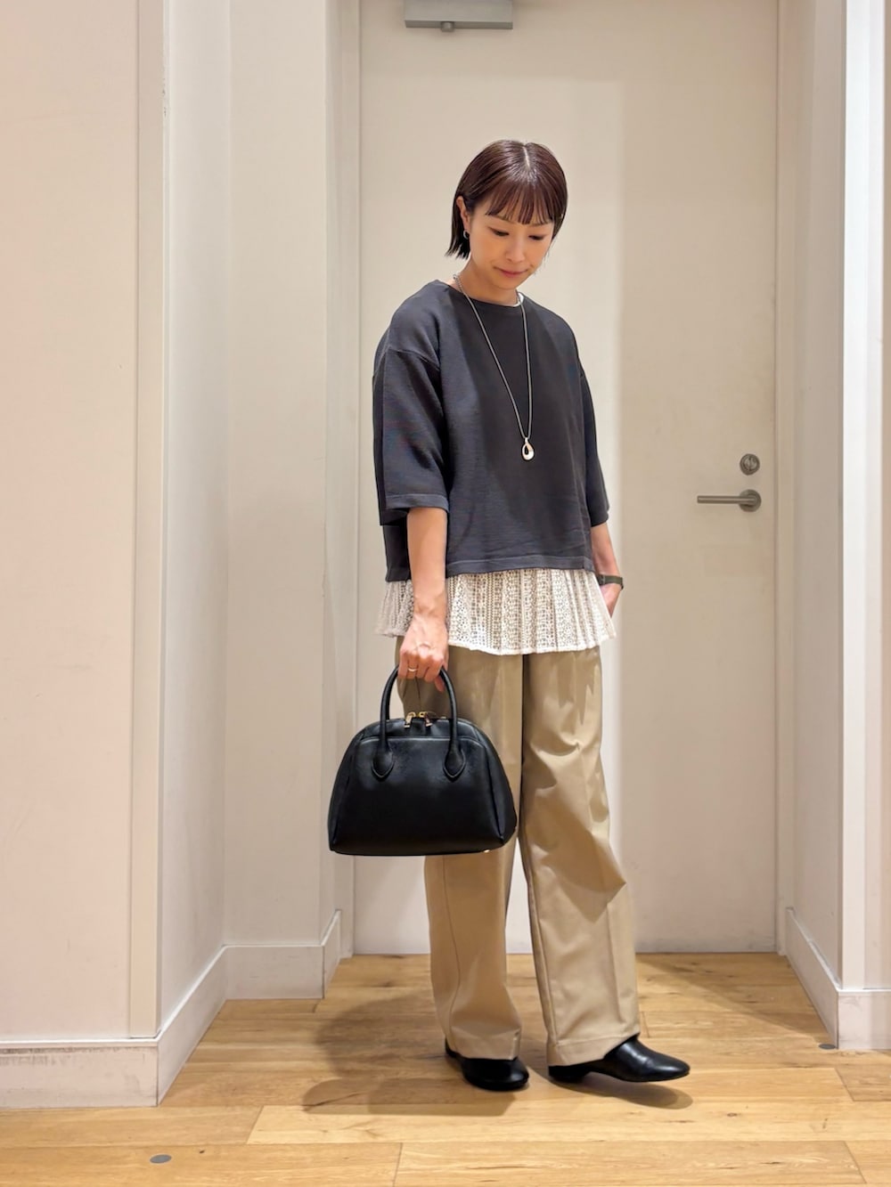 グレー系のニット/セーター、ベージュ系のその他パンツ、ブラック系のハンドバッグを着用したレディースの秋コーディネートの5枚目の写真