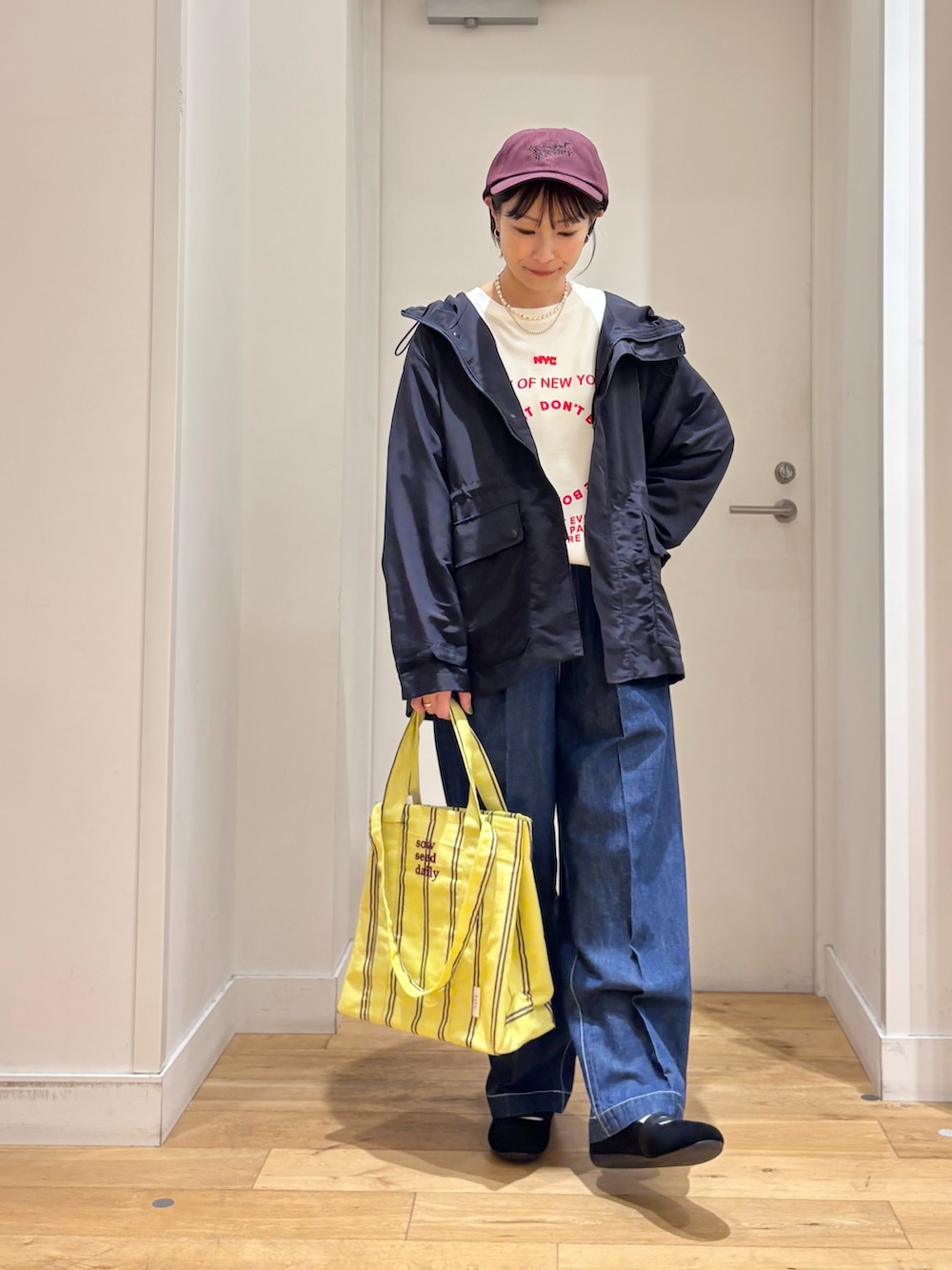 ブルー系のマウンテンパーカー、ホワイト系のTシャツ/カットソー、イエロー系のトートバッグを着用したレディースの春コーディネートの2枚目の写真