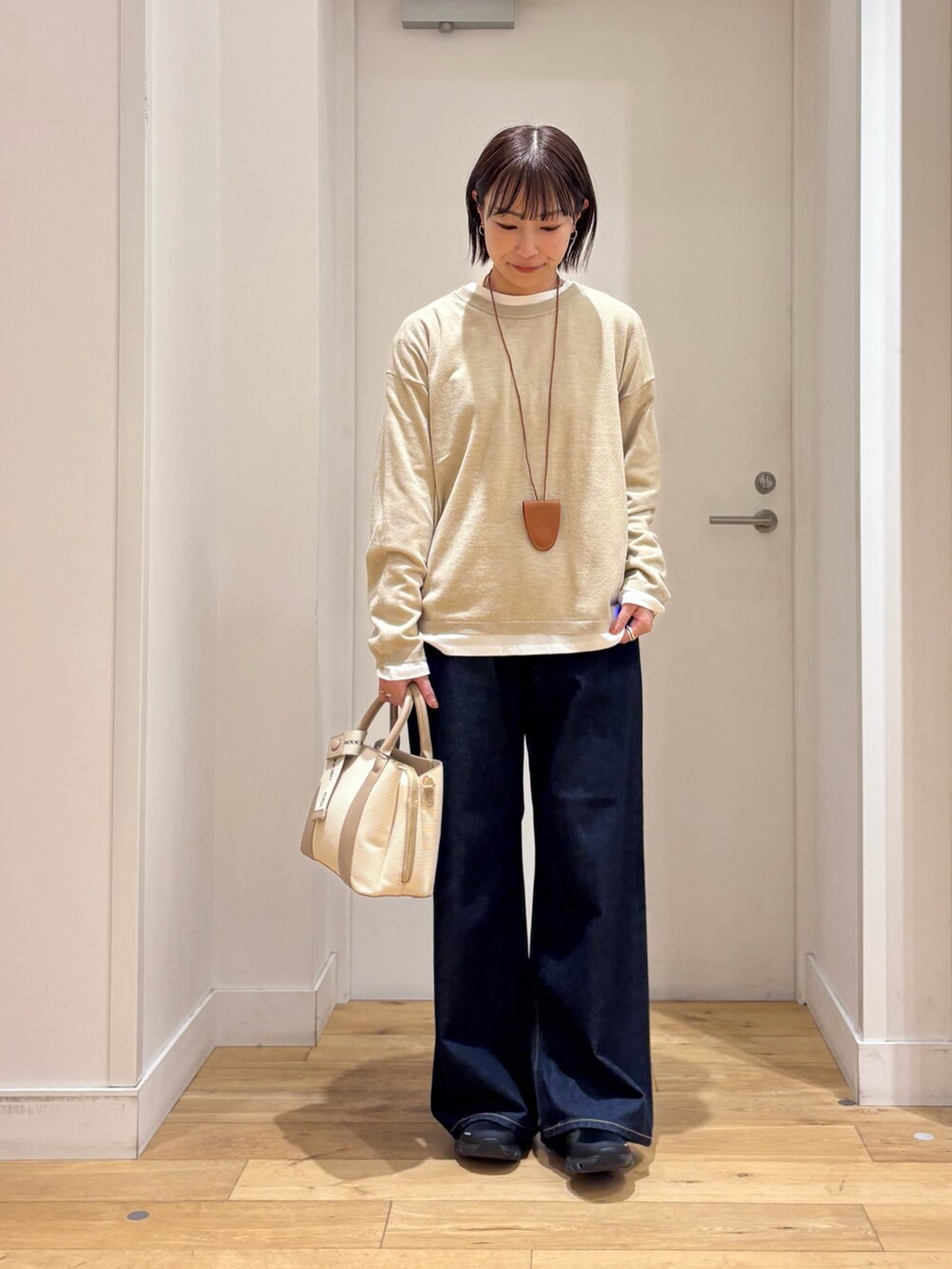 ベージュ系のブルゾン、ベージュ系のニット/セーター、ホワイト系のハンドバッグを着用したレディースの冬コーディネートの6枚目の写真