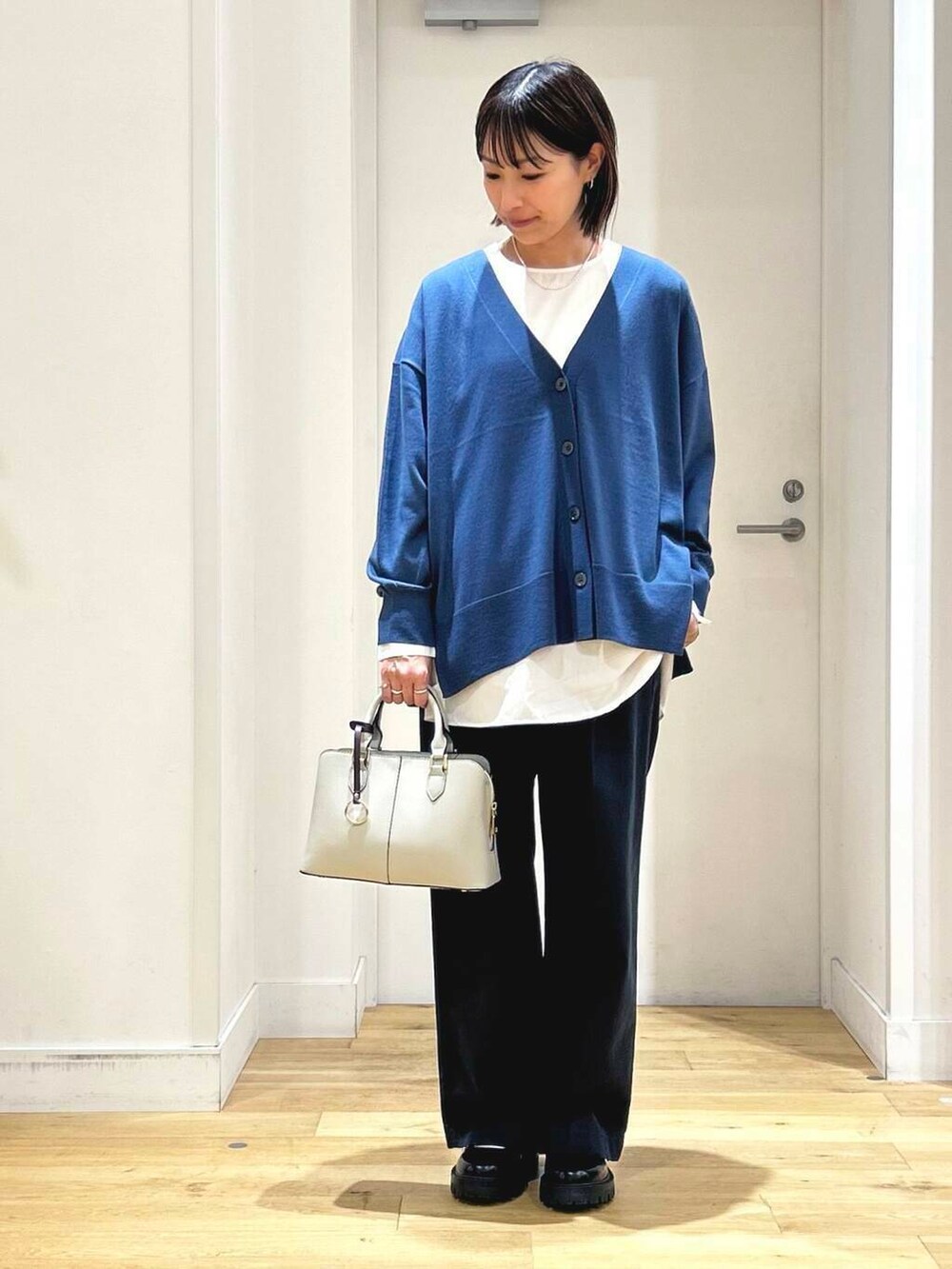 ブルー系のカーディガン/ボレロ、ホワイト系のシャツ/ブラウス、グレー系のハンドバッグを着用したレディースの秋コーディネートの3枚目の写真