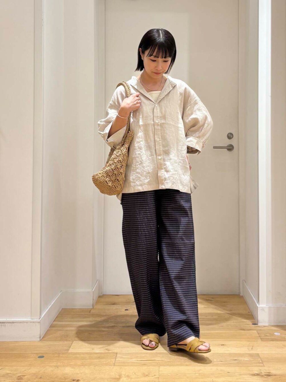 ベージュ系のシャツ/ブラウス、ベージュ系のトートバッグ、イエロー系のサンダルを着用したレディースの夏コーディネートの3枚目の写真