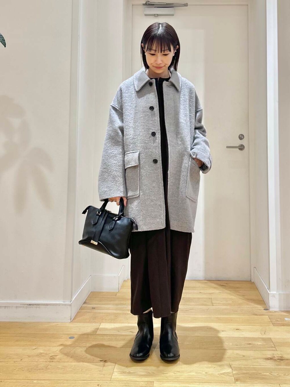 グレー系のその他アウター、ブラック系のボストンバッグ、ブラック系のブーツを着用したレディースの冬コーディネートの2枚目の写真