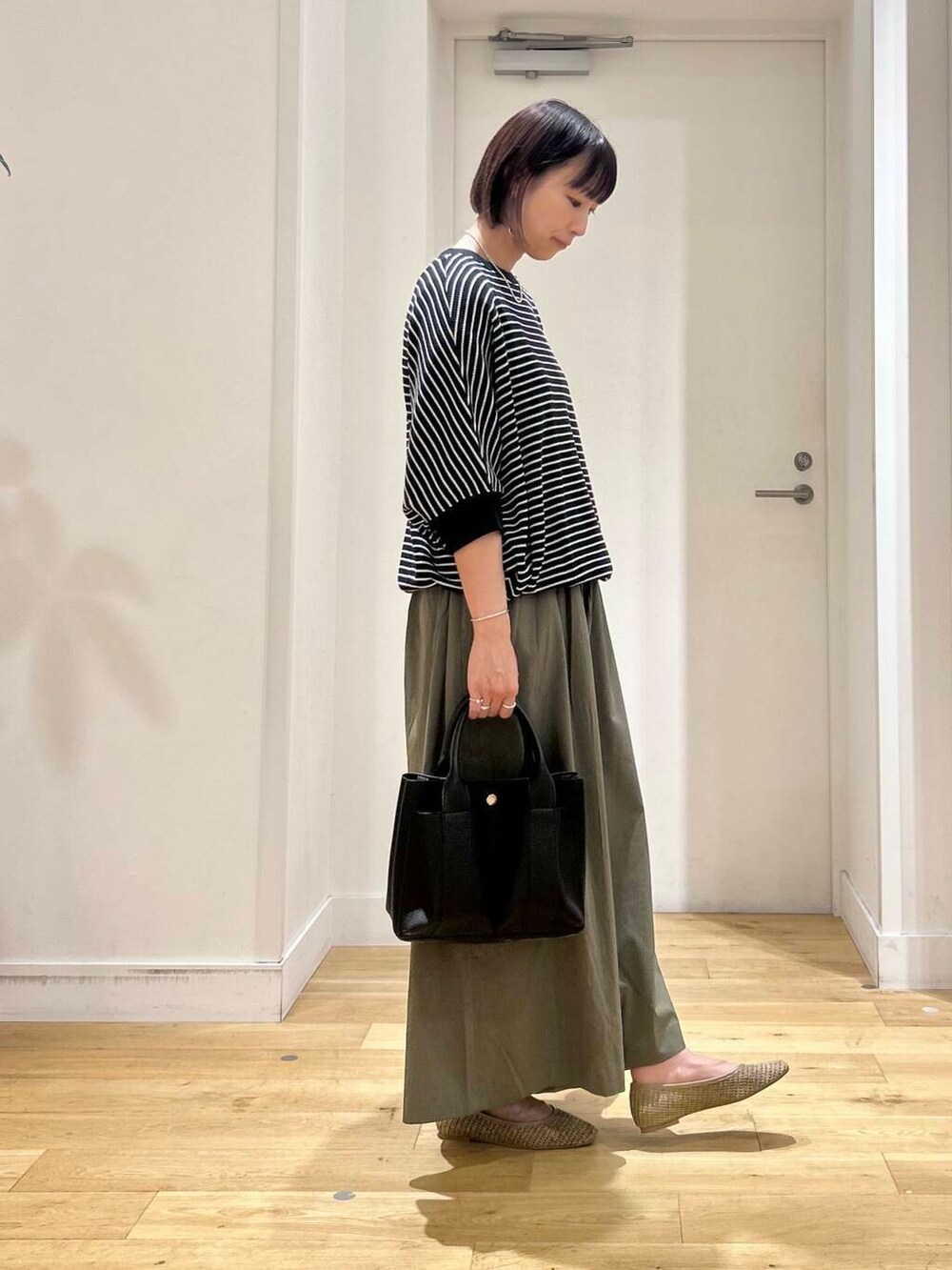 ブラック系のトートバッグ、グリーン系のその他パンツ、ベージュ系のパンプスを着用したレディースの夏コーディネートの4枚目の写真