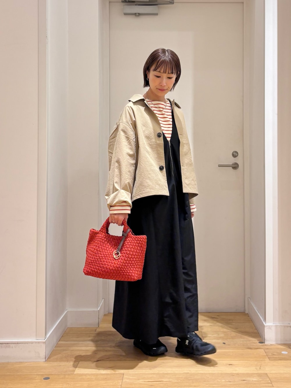 ブラック系のワンピース、ベージュ系のステンカラーコート、ホワイト系のTシャツ/カットソーを着用したレディースの秋コーディネートの5枚目の写真