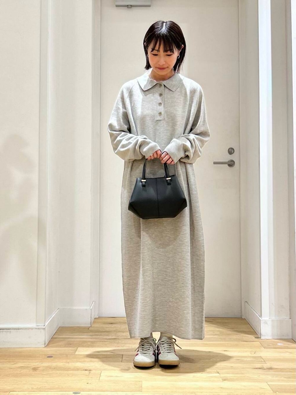 ブラック系のショルダーバッグ、グレー系のワンピース、ホワイト系のスニーカーを着用したレディースの秋コーディネートの2枚目の写真