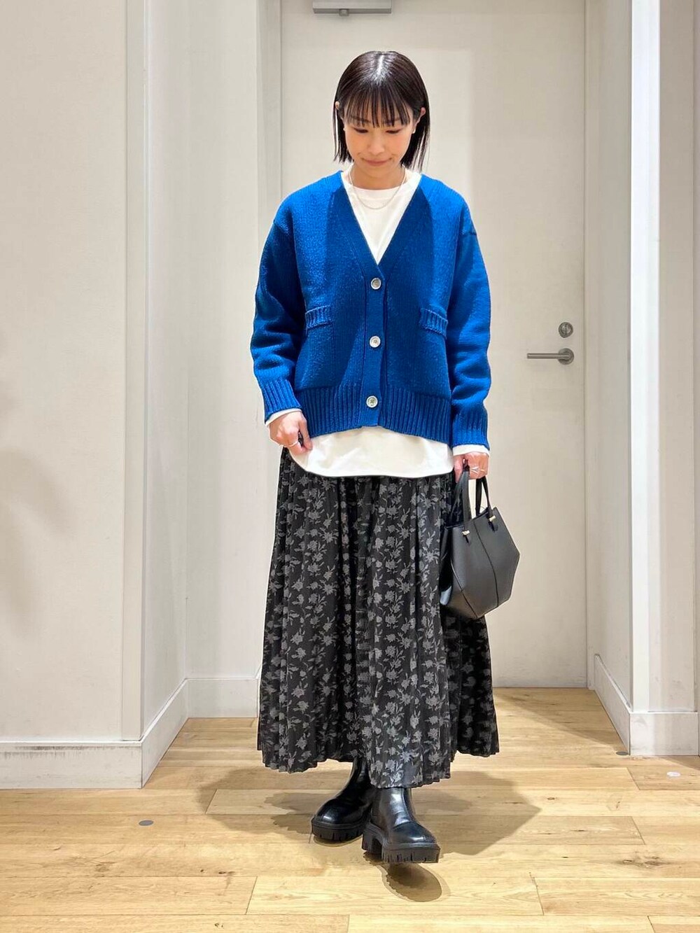 ブラック系のショルダーバッグ、ブラック系のブーツ、ブルー系のカーディガン/ボレロを着用したレディースの冬コーディネートの2枚目の写真