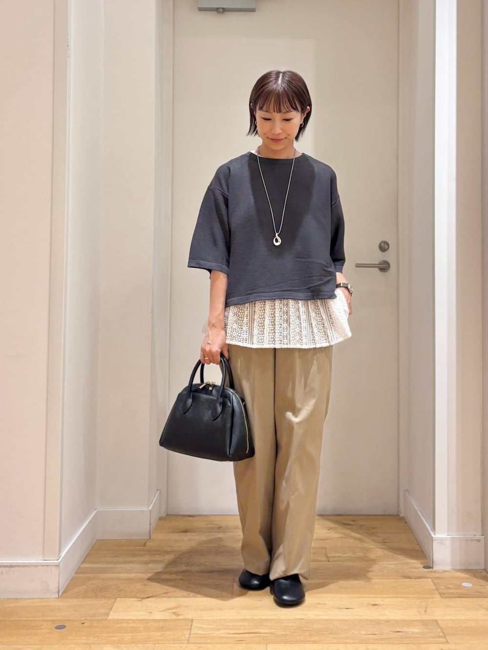 グレー系のニット/セーター、ベージュ系のその他パンツ、ブラック系のハンドバッグを着用したレディースの秋コーディネートの2枚目の写真