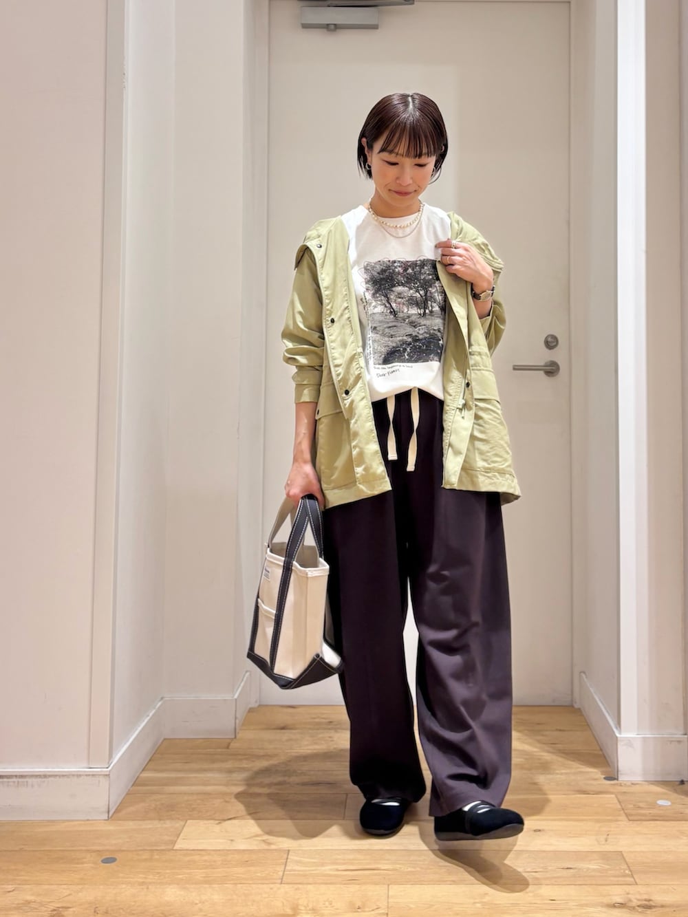 グリーン系のマウンテンパーカー、ホワイト系のTシャツ/カットソー、ブラック系のスニーカーを着用したレディースの春コーディネートの3枚目の写真