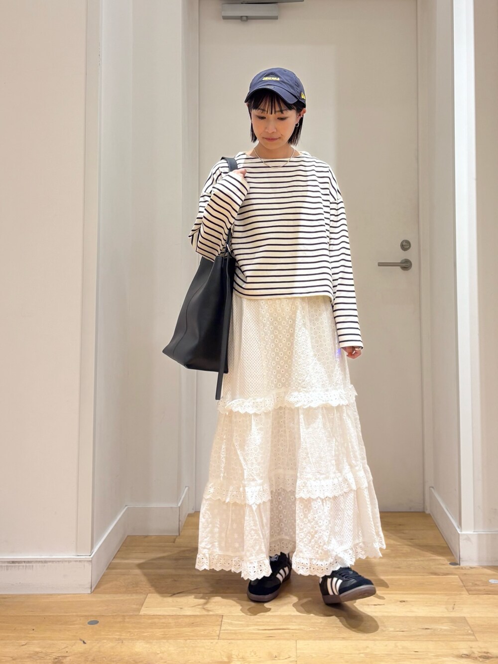 ホワイト系のTシャツ/カットソー、ホワイト系のスカート、ブラック系のショルダーバッグを着用したレディースの秋コーディネートの2枚目の写真