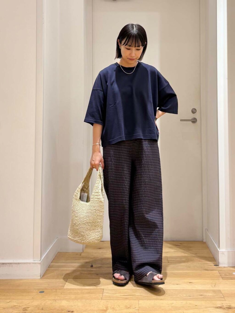 ベージュ系のトートバッグ、グレー系のサンダル、ブルー系のTシャツ/カットソーを着用したレディースの夏コーディネートの3枚目の写真