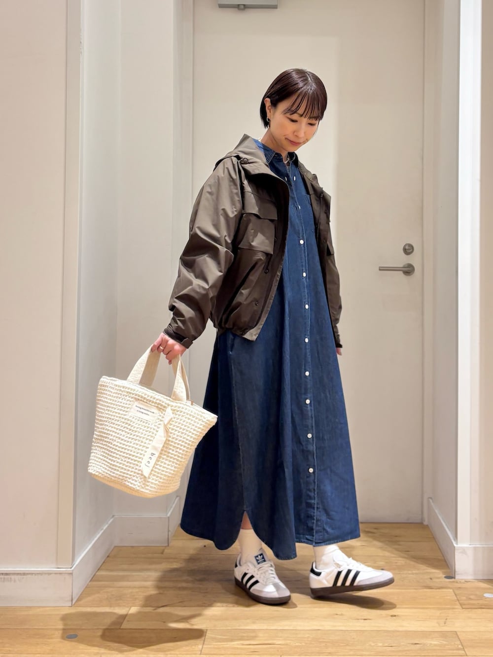 ブラウン系のナイロンジャケット、ブルー系のワンピース、ホワイト系のスニーカーを着用したレディースの春コーディネートの6枚目の写真