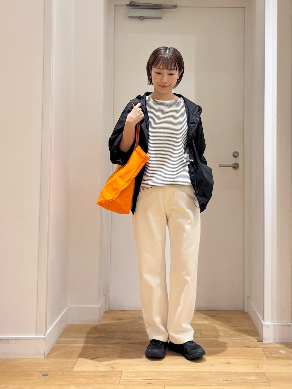 ホワイト系のTシャツ/カットソー、ブラック系のナイロンジャケット、ベージュ系のその他パンツを着用したレディースの夏コーディネートの3枚目の写真