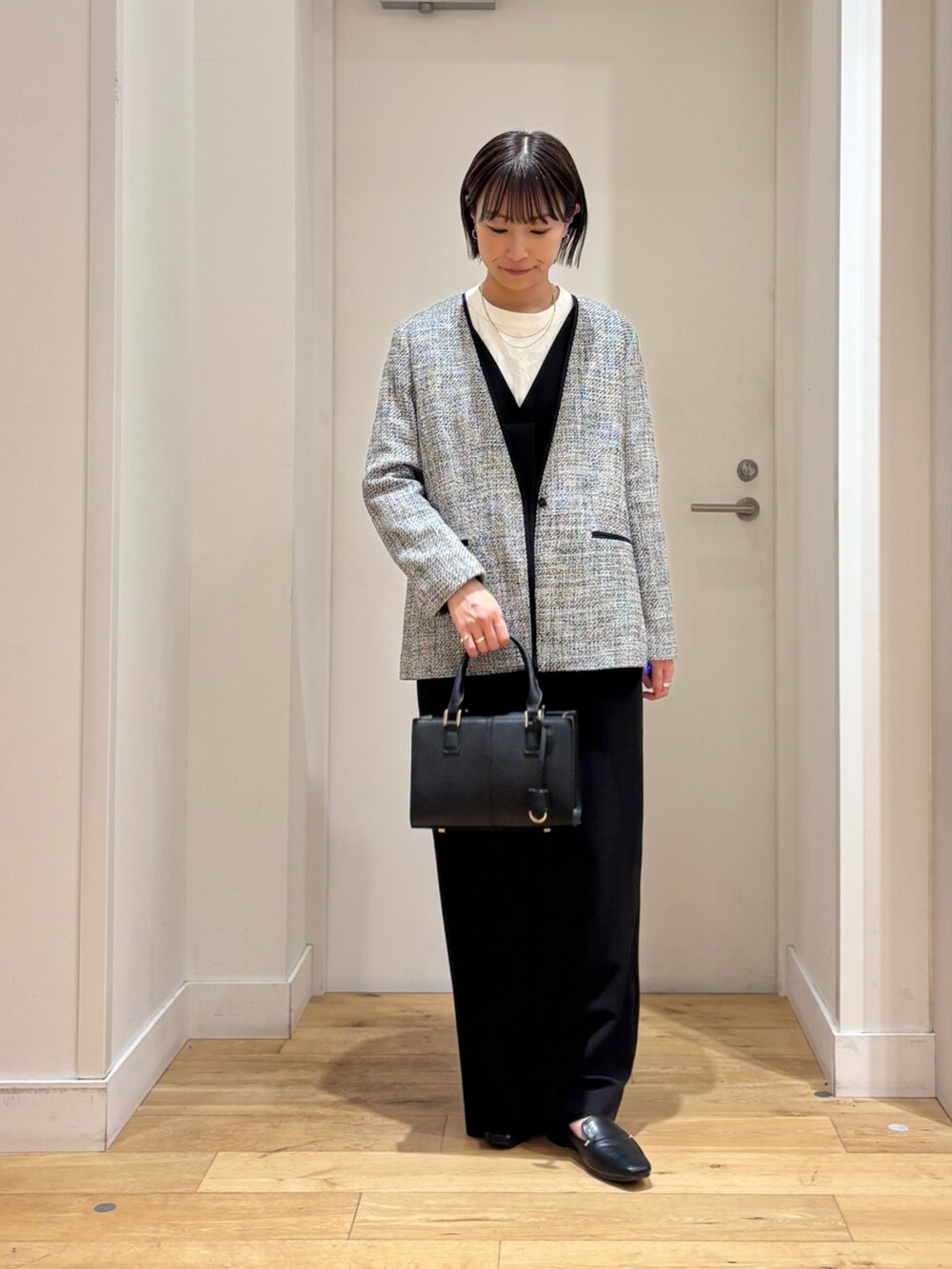 ブラック系のスーツジャケット、ホワイト系のシャツ/ブラウス、ブラック系のハンドバッグを着用したレディースの冬コーディネートの3枚目の写真