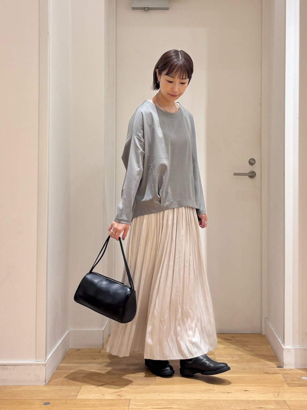 ブルー系のTシャツ/カットソー、ブラック系のハンドバッグ、ブラック系のレインシューズを着用したレディースの秋コーディネートの6枚目の写真
