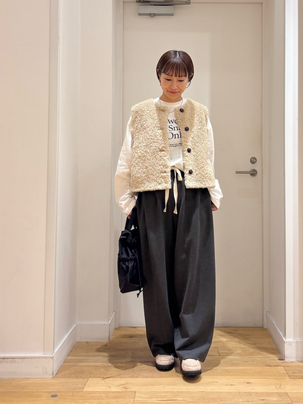 ベージュ系のダウンベスト、グレー系のその他パンツ、ホワイト系のTシャツ/カットソーを着用したレディースの秋コーディネートの3枚目の写真